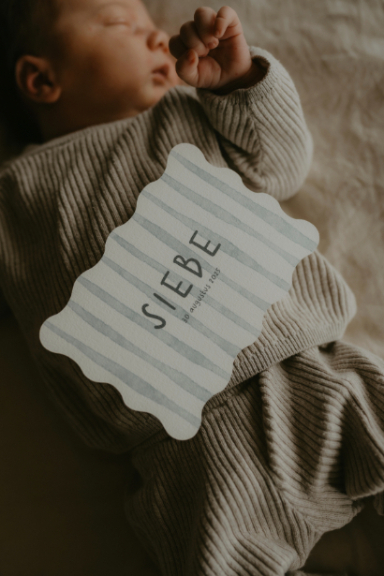 Geboortekaartje in golvende vorm met blauwe waterverf streepjes