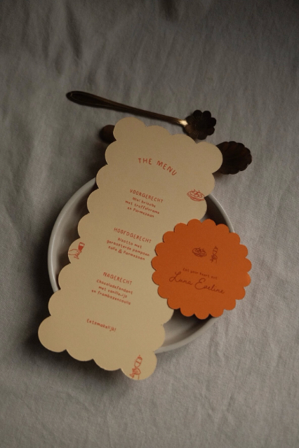 Menukaart in gele kleur en langwerpig bobbel vorm, met naamkaartje oranje in bloemvorm